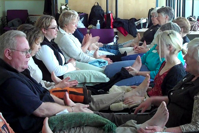 Reflexology students practicing on each other’s feet during a hands-on training class